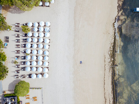 Indonesia, Bali, Aerial view of rows of beach umbrellas on sandy coastal beach of Nusa Dua