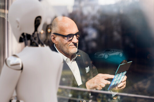 Senior businessman using digital tablet, looking for computerised cars