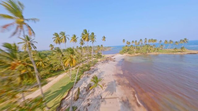 FPV Flight Over Playa Los Coquitos With Glistening Water Of Sea On A Sunny Day In Summer In Cabrera, Dominica, Republic. - aerial
