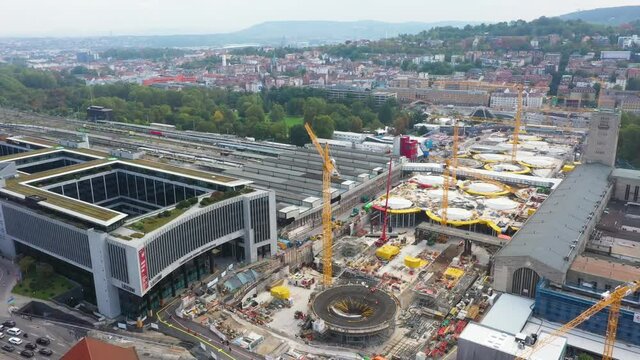 Aerial of huge railroads and construction site of main train station Stuttgart S21 with cranes and construction workers descending over Stuttgart, Germany.