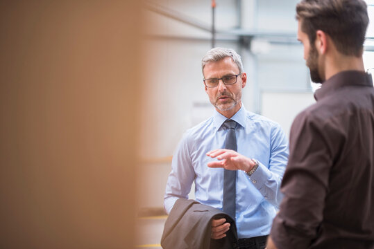 Two businessmen talking in a factory