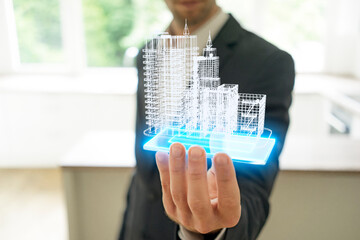 Businessman holding hologram of architectural model