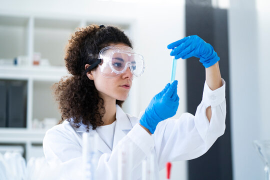Young female scientist examining test tube at chemistry lab