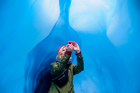 Woman taking a picture in an ice cave, Fox Glacier, South Island, New Zealand