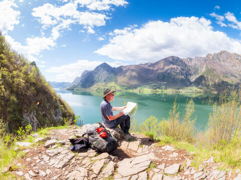 Italy, Lombardy, spring at Lake Idro, hiker sitting with map at observation point