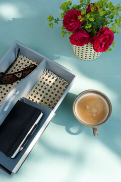 Coffee, red roses and handmade desk organizer with sunglasses and notebook