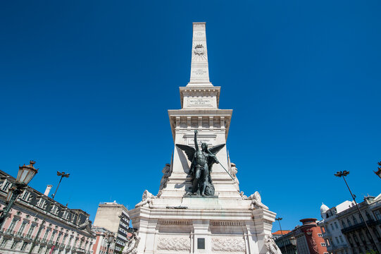 Low angle view of Monument to the Restorers against clear blue sky in Restauradores Square, Lisbon, Portugal