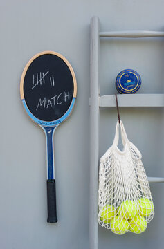 Blackboard made from tennis racket, ladder, small box and mesh bag with tennis balls