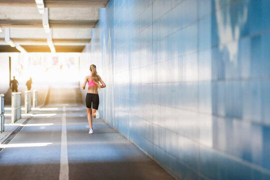Rear view of female jogger in tunnel
