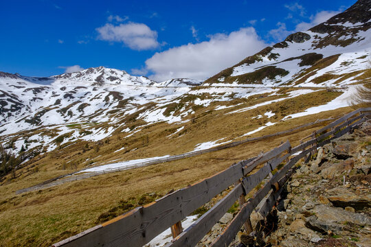 Italy, South Tyrol, Simple wooden fence in Penser Joch mountain pass with snow melting in background