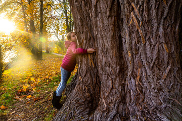 Girl hugging big tree in autumn