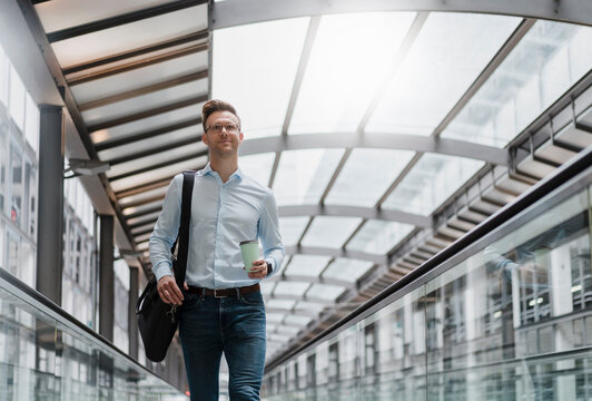 Businessman with coffee cup looking away in city