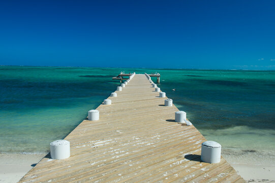 Fototapeta Diminishing perspective of pier over sea against clear blue sky during sunny day, Providenciales, Turks And Caicos Islands