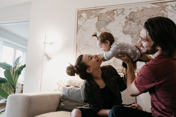 Happy family playing with baby girl in living room at home