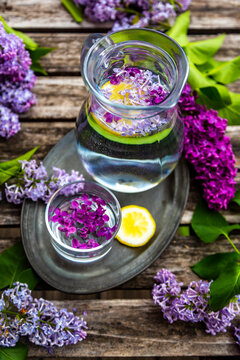 Jar with glass of water with lilac sirup and lemon