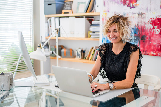 Smiling female instructor using laptop on table in cooking school