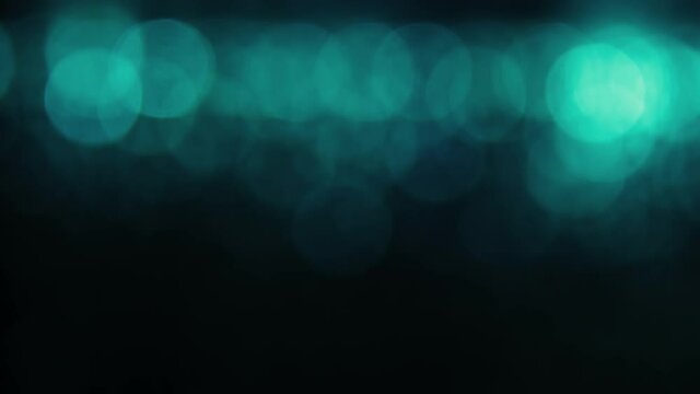 blue green abstract background with defocused bright boken lights on dark, seamless loop background