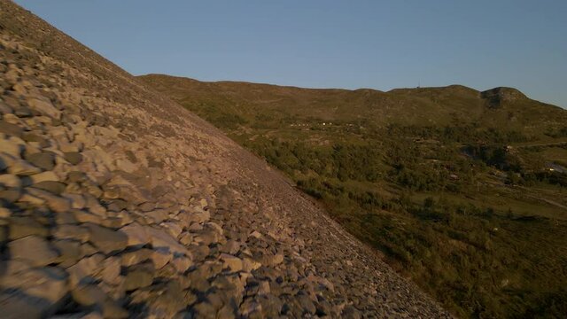 Gliding aerial shot of Sysen Dam rocky wall, Hordaland county, Norway