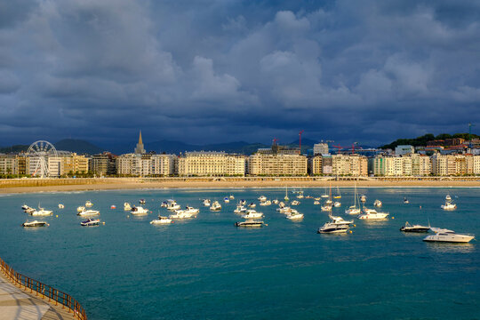 Spain, Gipuzkoa, San Sebastian, Storm clouds over various boats floating in Bay of La Concha