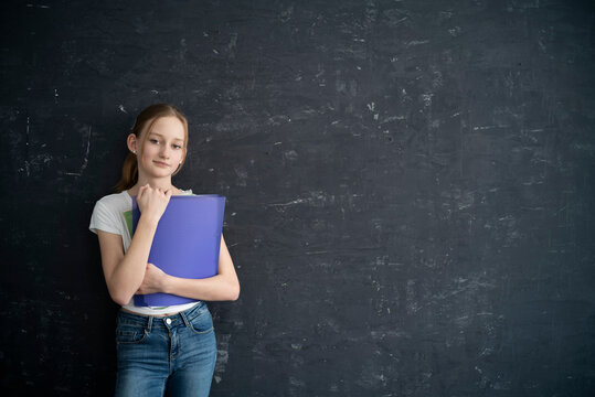 Girl with exersice books in front of black wall