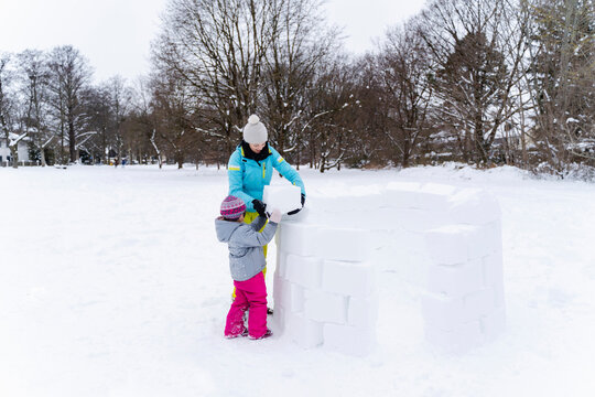 Mother and daughter building igloo at park