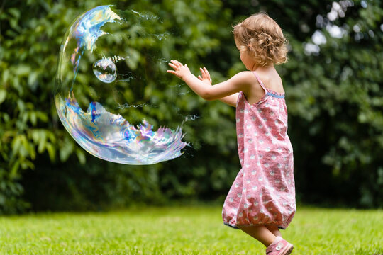 Cute girl exploding bubble at public park
