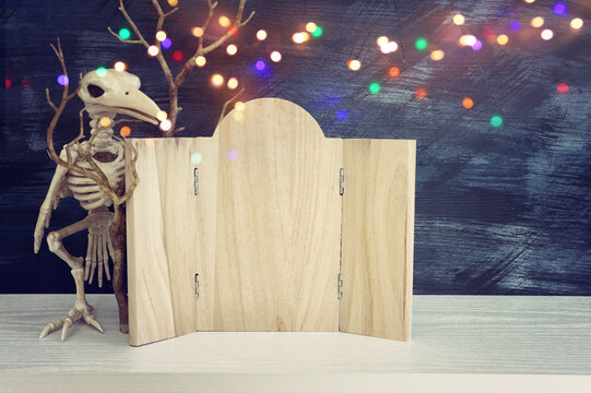 holidays image of Halloween. bird skeleton and wooden board frame for text or mock up over table