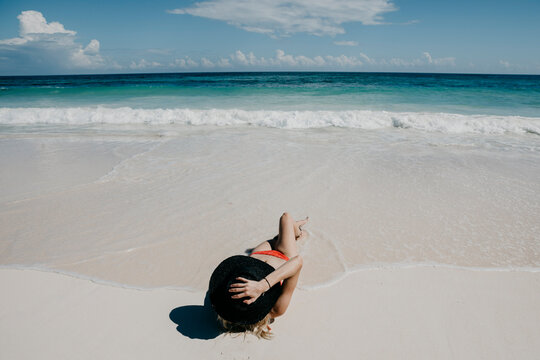 Mexico, Quintana Roo, Tulum, young woman with hat lying on the beach