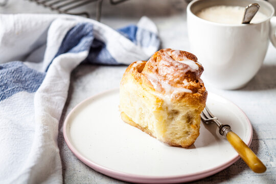 Home-baked cinnamon bun with icing sugar and a cup of coffee