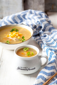 Bowls of homemade chicken stock with potatoes, carrots and parsley