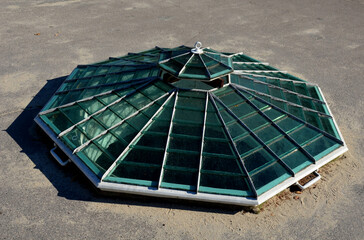 polygonal window at ground level in the shape of a hexagonal pyramid with ventilation in the shape of a lid. The window consists of many small glasses. Victorian style skylight orangery.