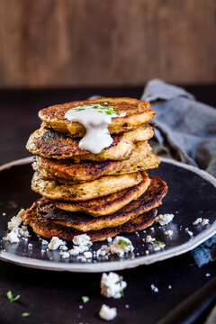 Stack of zucchini fritters with garlic yogurt sauce and feta