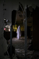 Blanket ghost stands in an abandoned asylum.