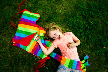 Happy girl holding colorful kite while lying down in park