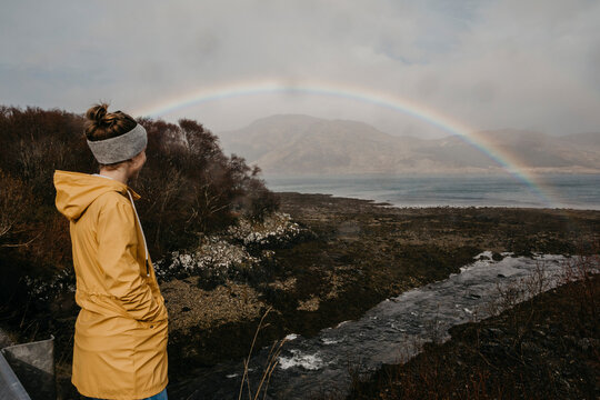 UK, Scotland, Highland, woman looking at rainbow above the sea