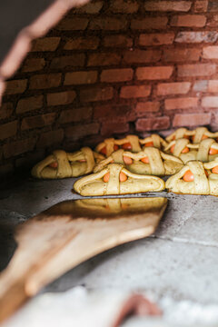 Close-up of pizza peel arranging Mona De Pascua in wood burning stove