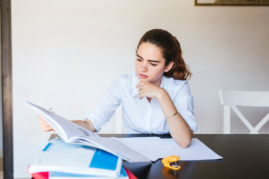 Focused female student learning at desk at home