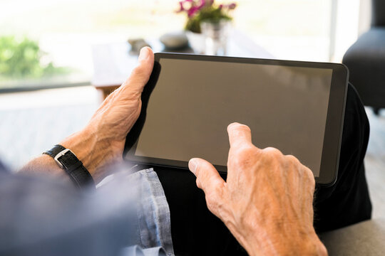 Close-up of senior man using tablet at home