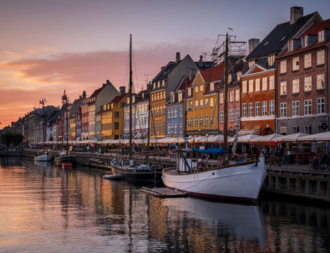 Denmark, Copenhagen, Boats moored along Nyhavn promenade at dusk with row of historical townhouses in background