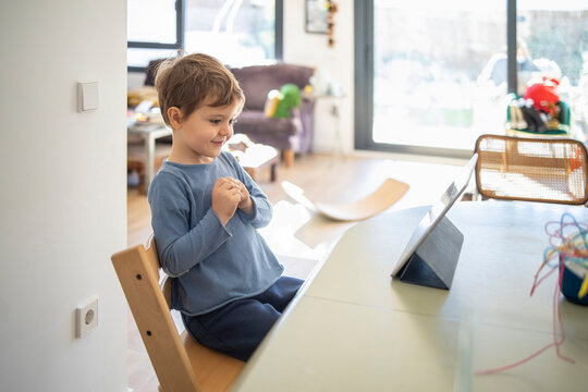 Smiling boy attending online class on digital tablet at home