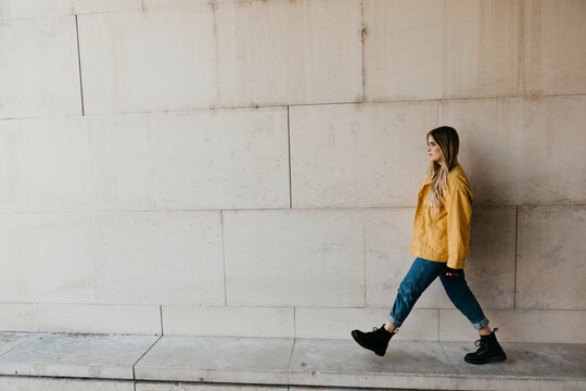 Walking young woman wearing yellow jacket