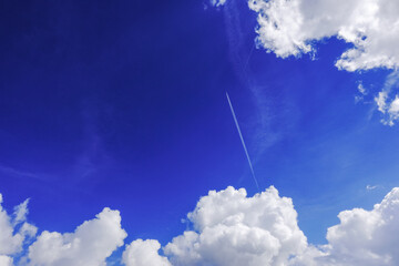 deep blue sky and a aeroplane flies out of a white cloud