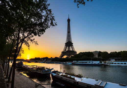 Eiffel Tower by Seine river against clear blue sky during sunrise, Paris, France