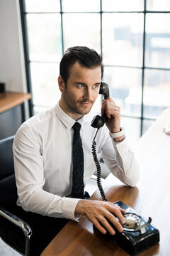 Businessman in office using vintage retro telephone