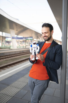 Smiling businessman looking at robot while standing on railroad platform