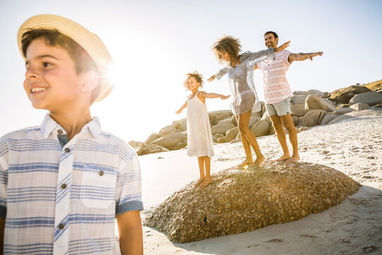Happy family balancing on a rock on the beach
