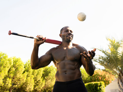 Male athlete with baseball in park during sunny day