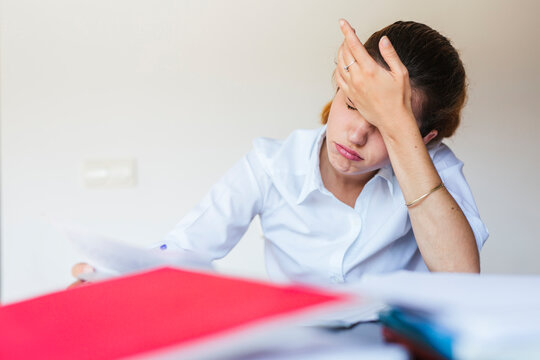 Frustrated female student with documents at desk at home
