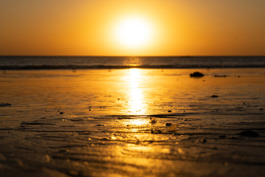 USA, California, Santa Monica, Setting sun illuminating wet sand of coastal beach