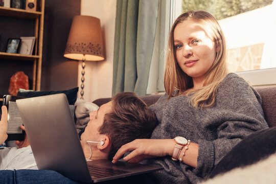 Young couple relaxing on sofa and using notebook, smartphone and ebook reader